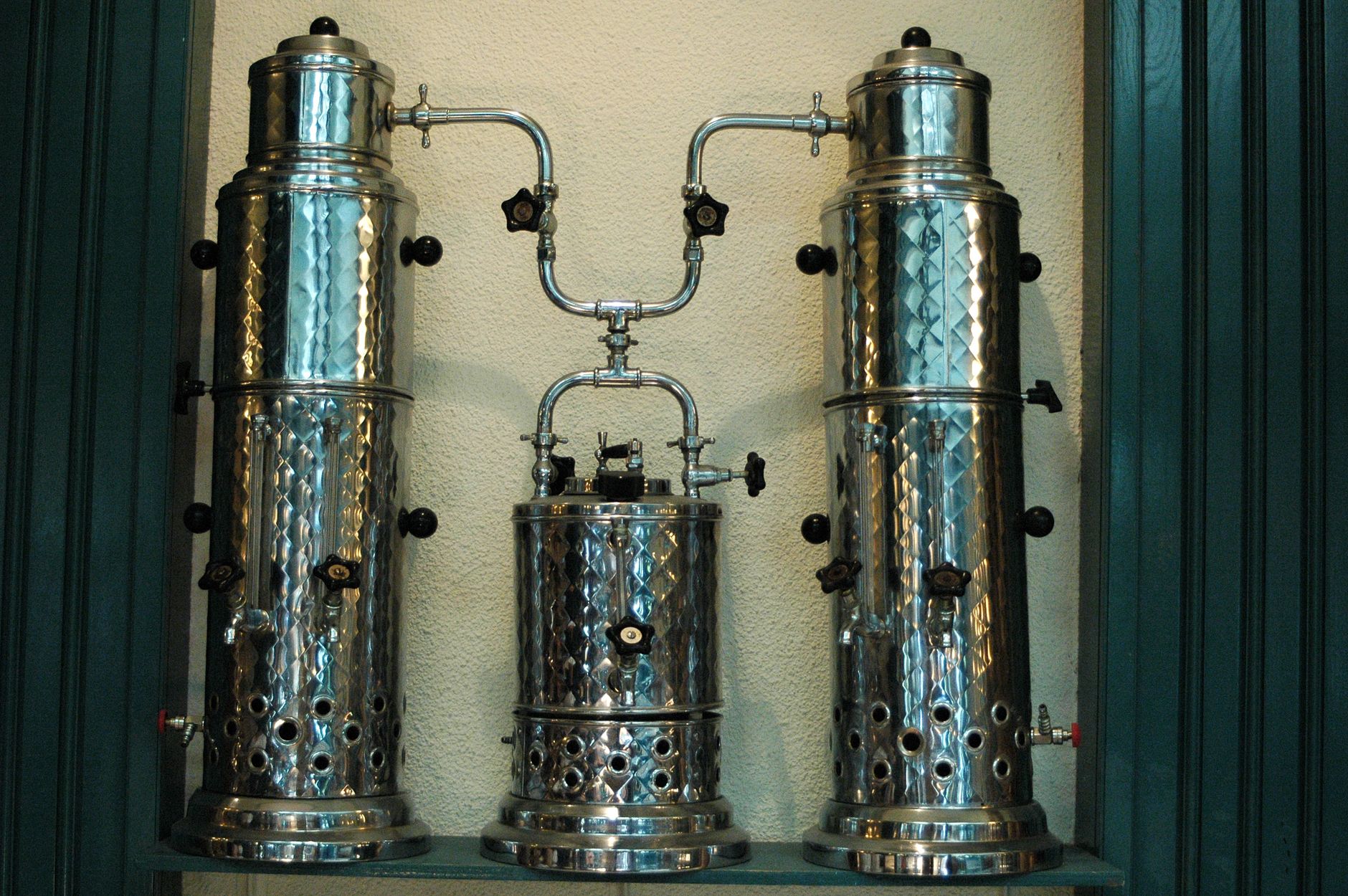 Three stainless steel coffee machines arranged on a shelf, showcasing vintage brewing equipment.