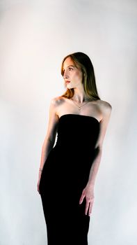 Portrait of a woman in a black strapless dress against a neutral background.