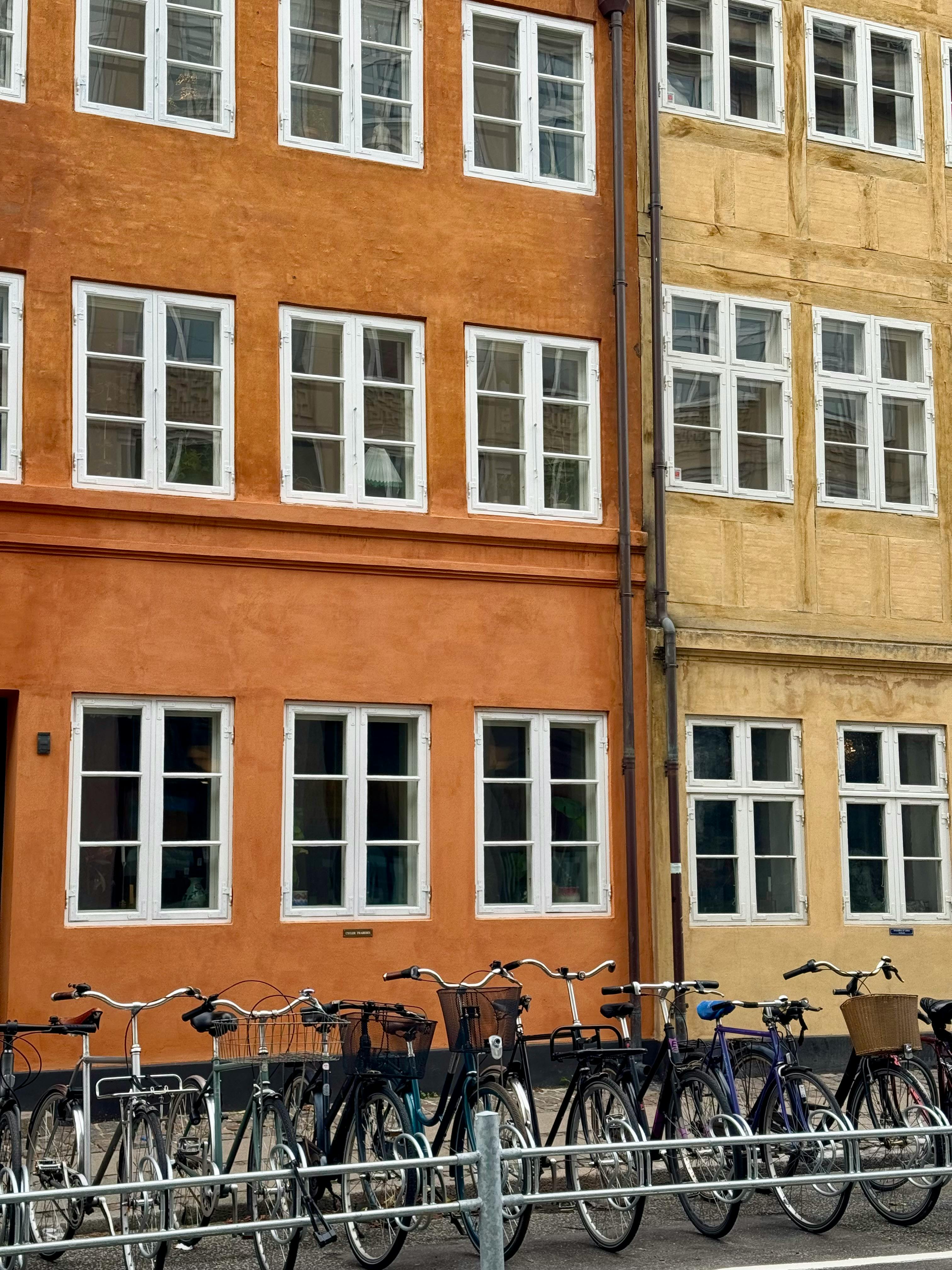 Bicycles lined up against vibrant buildings in Copenhagen's charming streets.