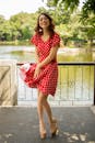 一位穿着红色圆点连衣裙的快乐女人，正在湖边享受阳光明媚的一天