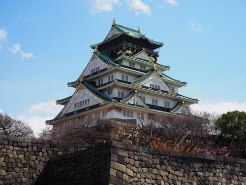 Free Historic Osaka Castle surrounded by spring foliage under a clear blue sky. Stock Photo