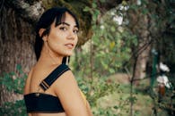 一位时尚的年轻女子自信地在郁郁葱葱的森林中摆出姿势，散发着自然之美