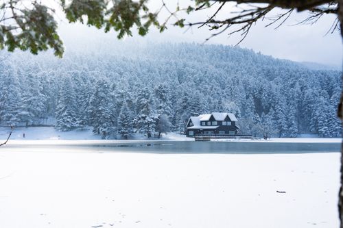 Free Serene winter scene of a snow-covered lake house surrounded by frosty forests in Bolu, Türkiye. Stock Photo