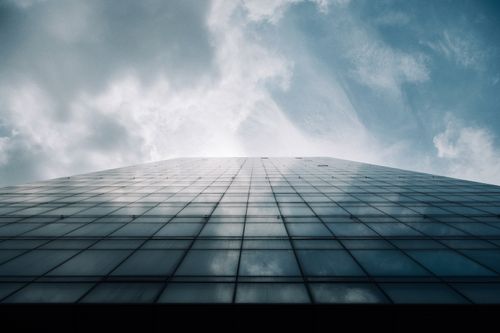 Free A modern skyscraper's glass facade reflecting the cloudy sky in Abuja. Stock Photo