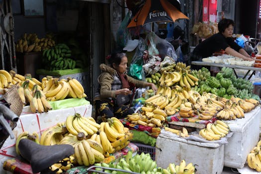 Vibrant banana market stall with vendor, offering a variety of fresh bananas in a busy street setting.