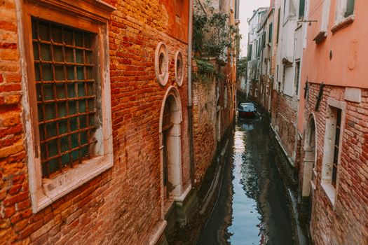 Scenic view of a narrow canal in Venice, Italy with historical brick architecture.