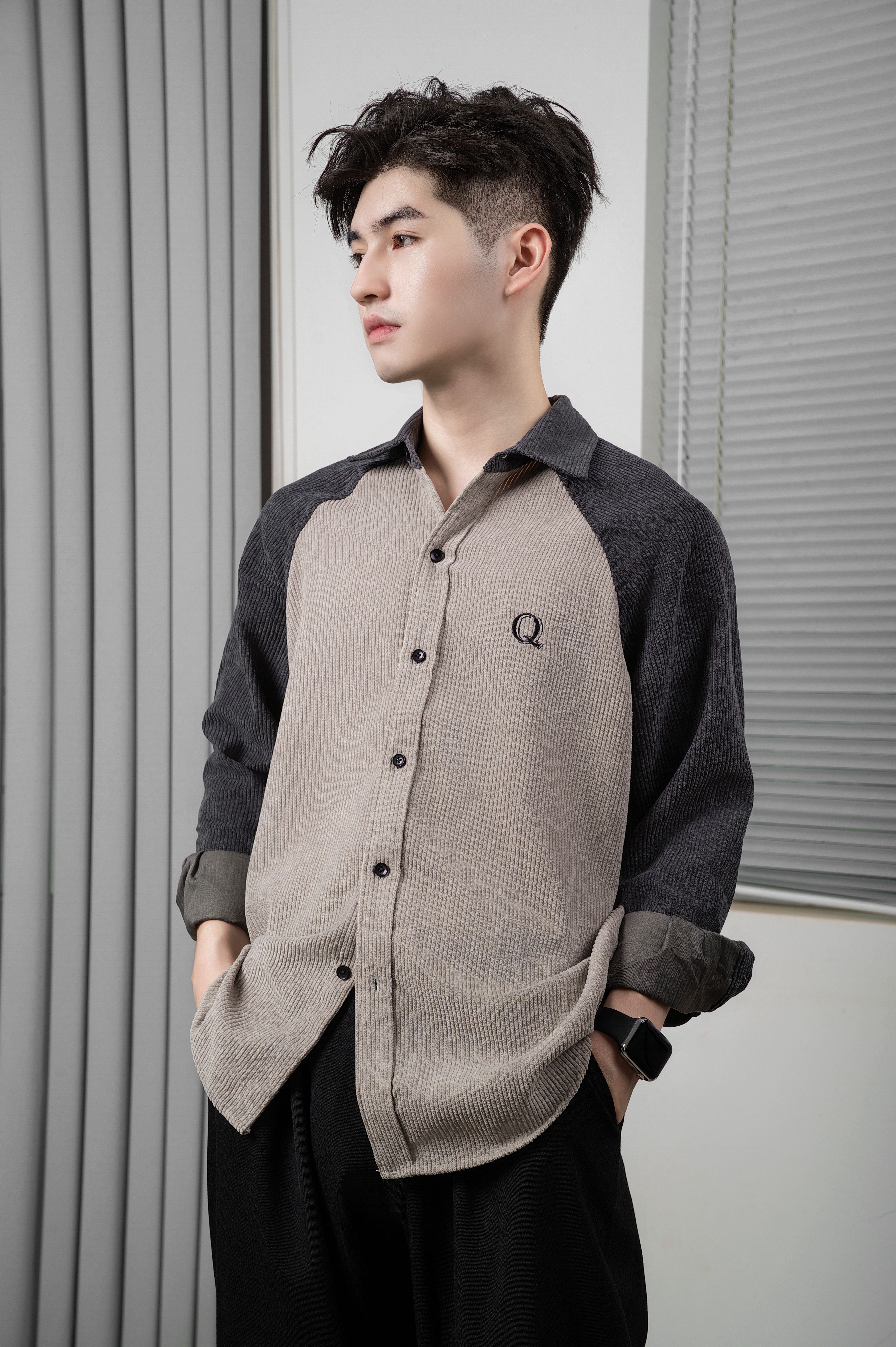 Young man wearing a stylish shirt indoors, looking thoughtful.