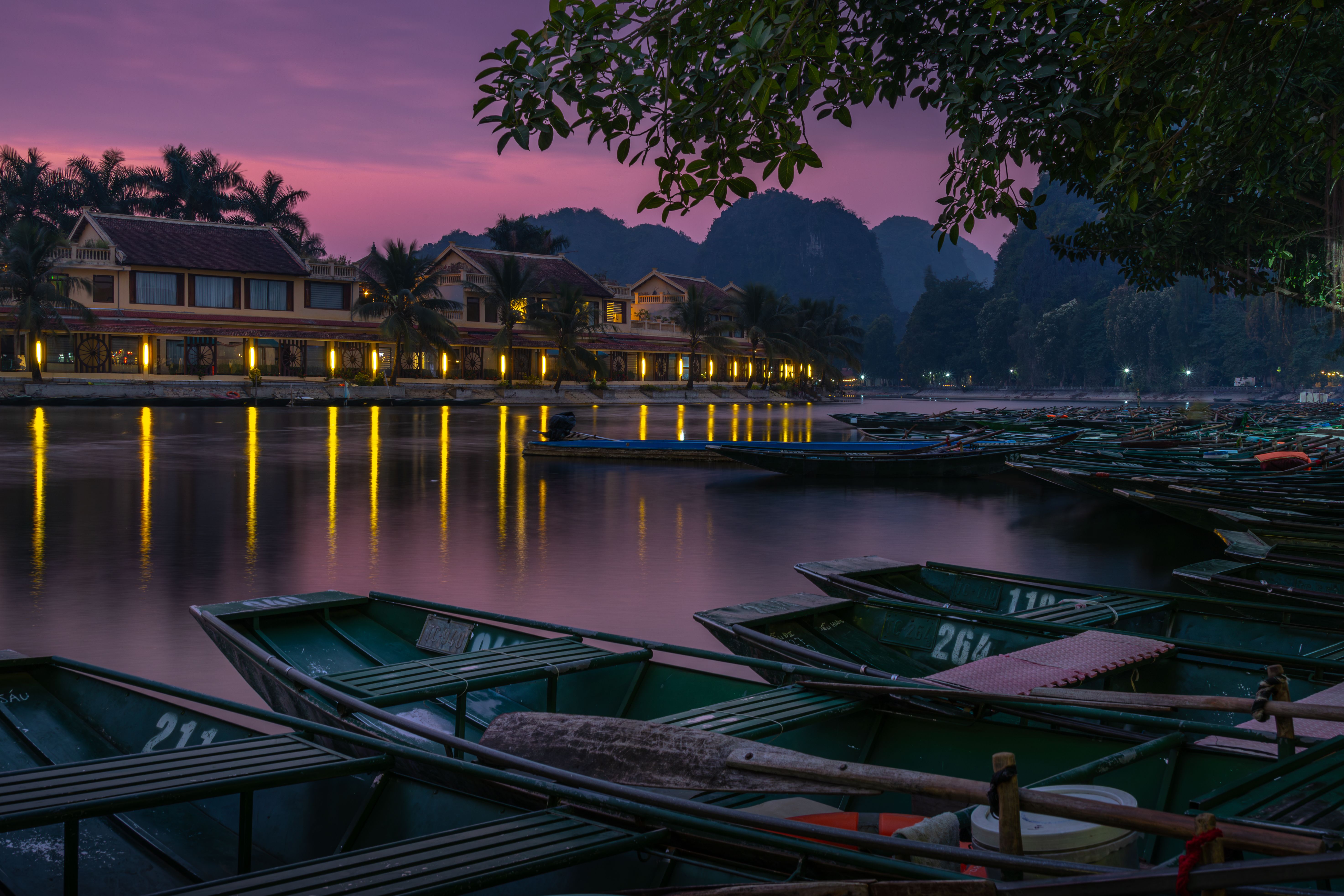 Enchanting twilight view of boats and waterfront homes in Hoa Lư, Vietnam.