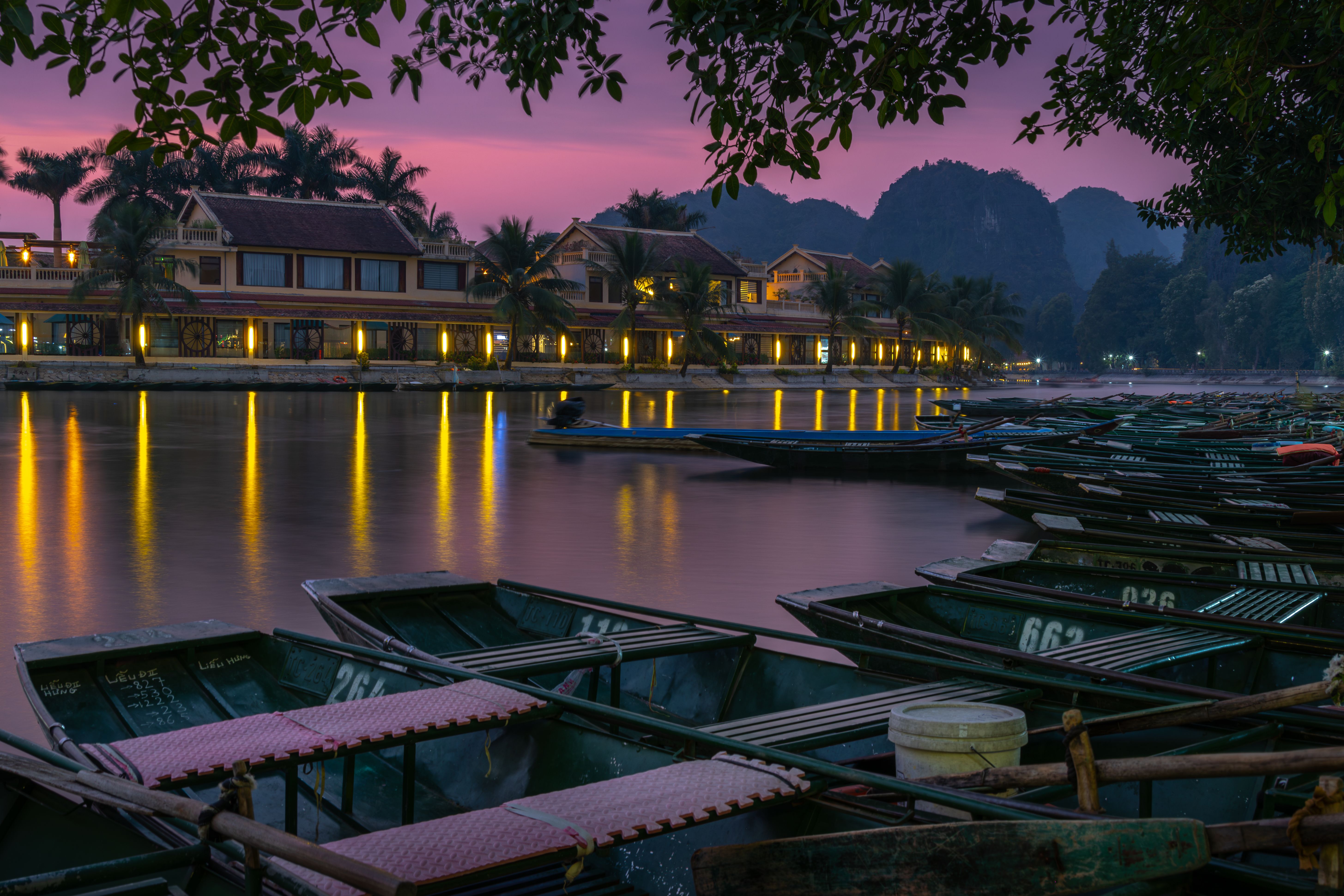 Tranquil evening view of boats and illuminated buildings in Hoa Lư, Vietnam.