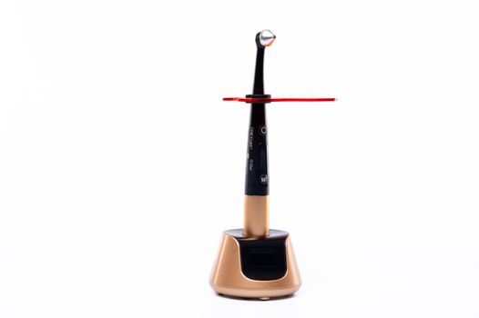 High-tech dental curing light with sleek black and gold design on a white background.