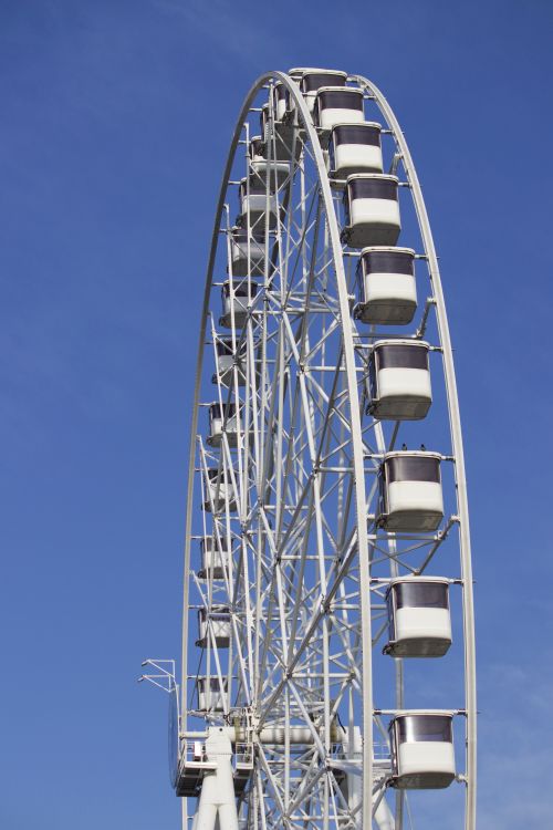 Free A towering ferris wheel set against a vivid blue sky capturing a perfect day. Stock Photo