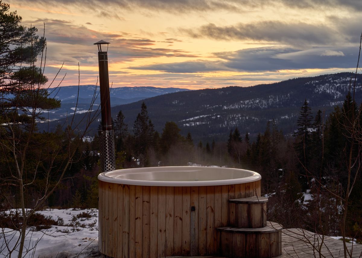 A wood-fired hot tub steaming above a mountain valley at sunset