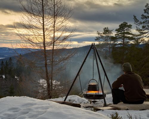 Free Outdoor winter cooking in Krøderen, Norway with a scenic snowy forest backdrop at sunset. Stock Photo