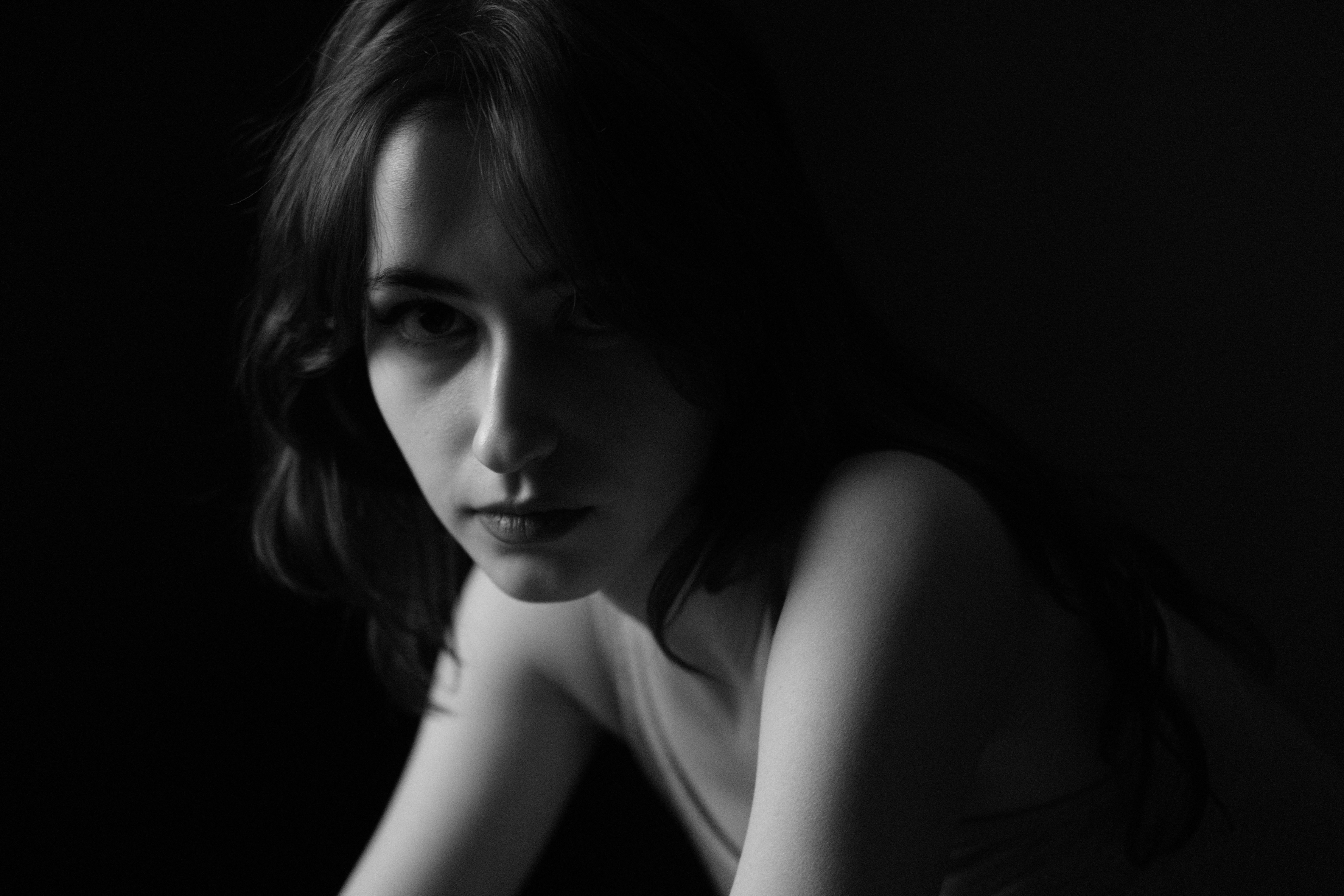 Emotive black and white portrait of a woman with dramatic shadows.