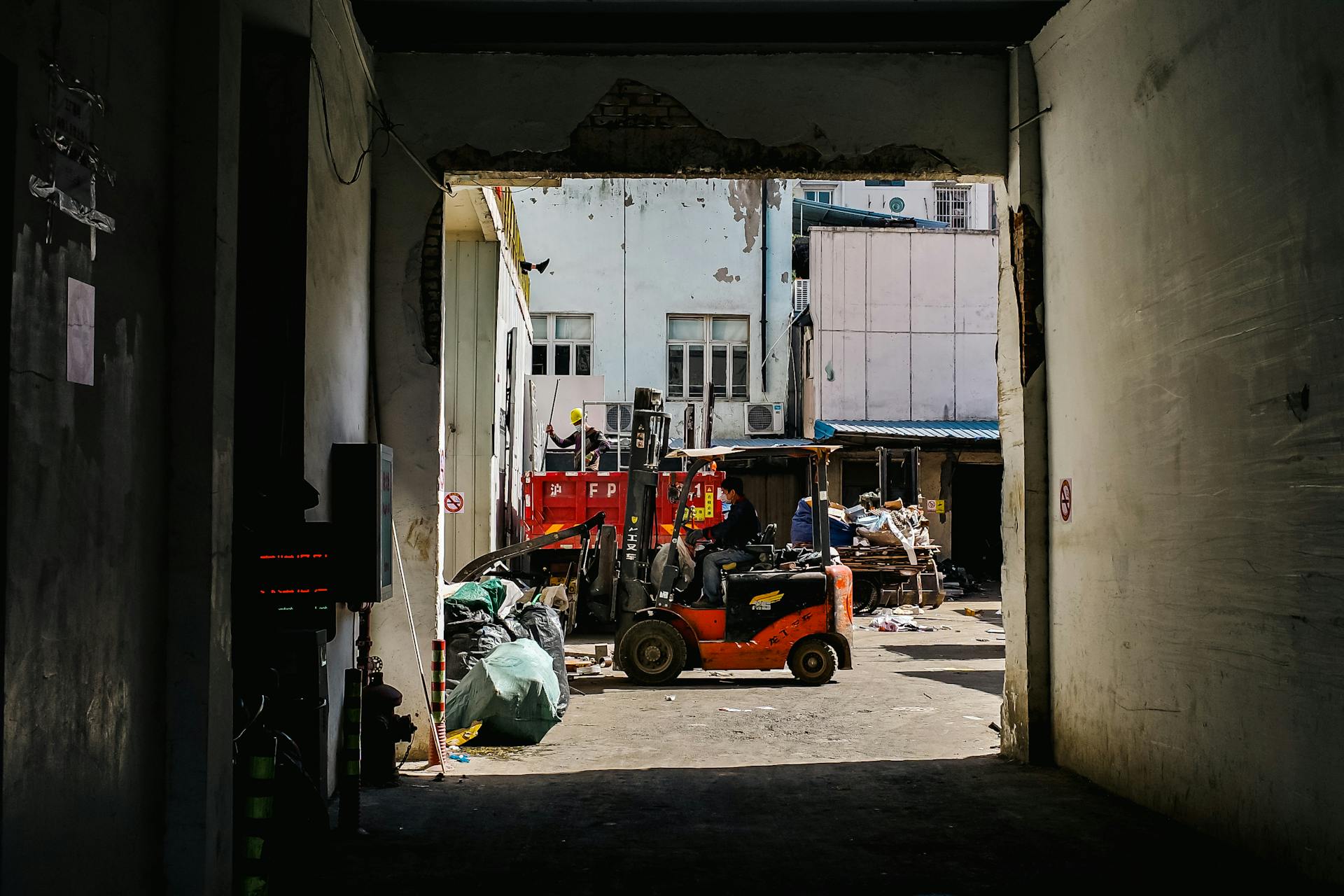 A bustling urban alleyway in Shanghai with a worker operating a forklift.