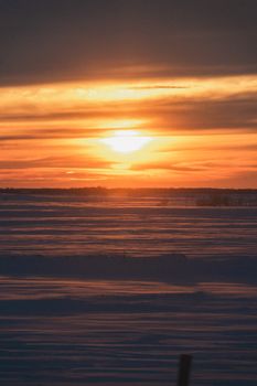 Beautiful winter sunset over a vast snowy field, showcasing the serene and tranquil nature of the season.