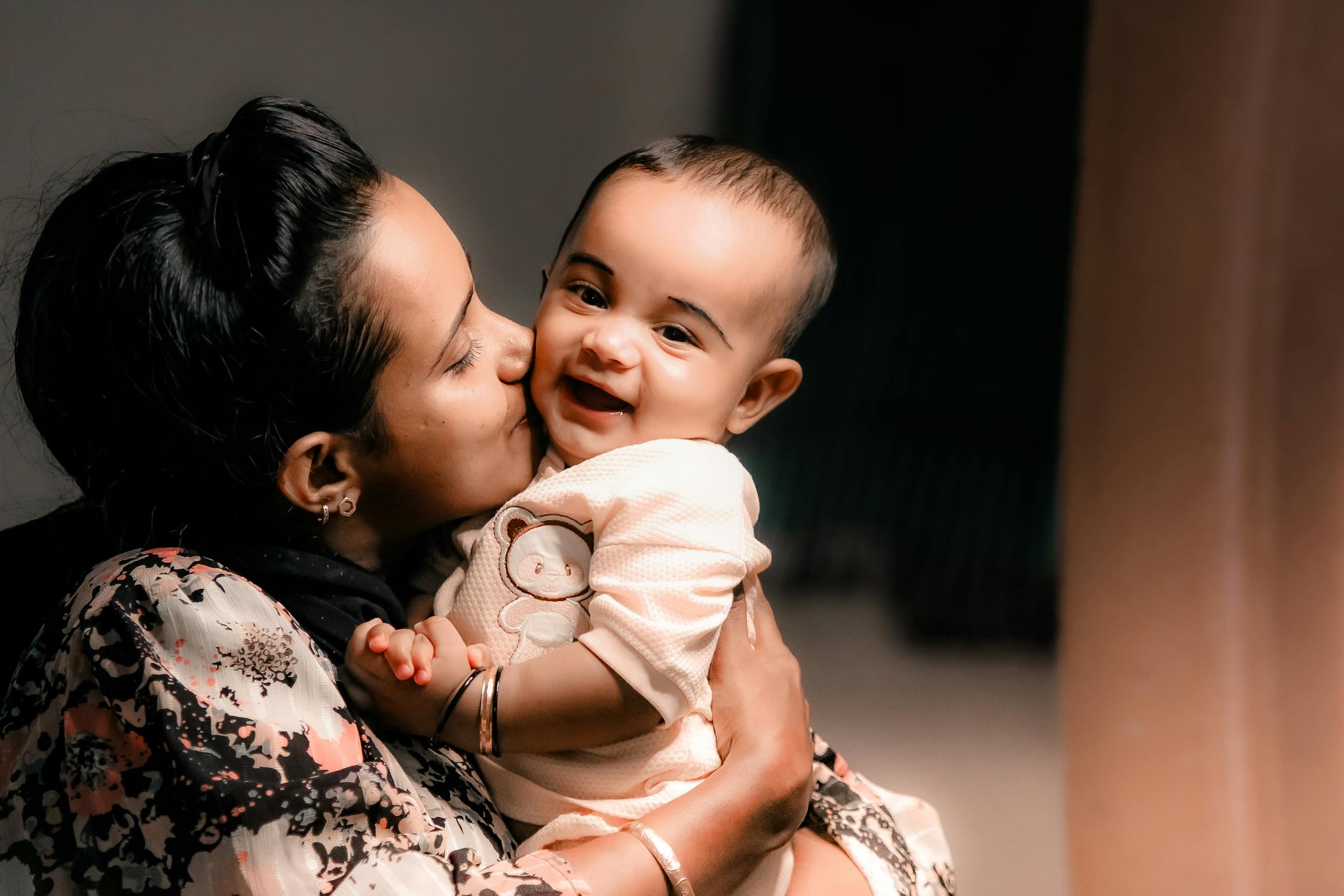 Mother Kissing Baby Indoors with Soft Lighting