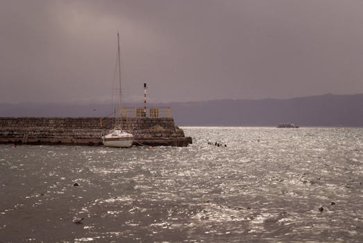 A tranquil scene of a boat docked at Ohrid Harbor under a moody sky, North Macedonia.