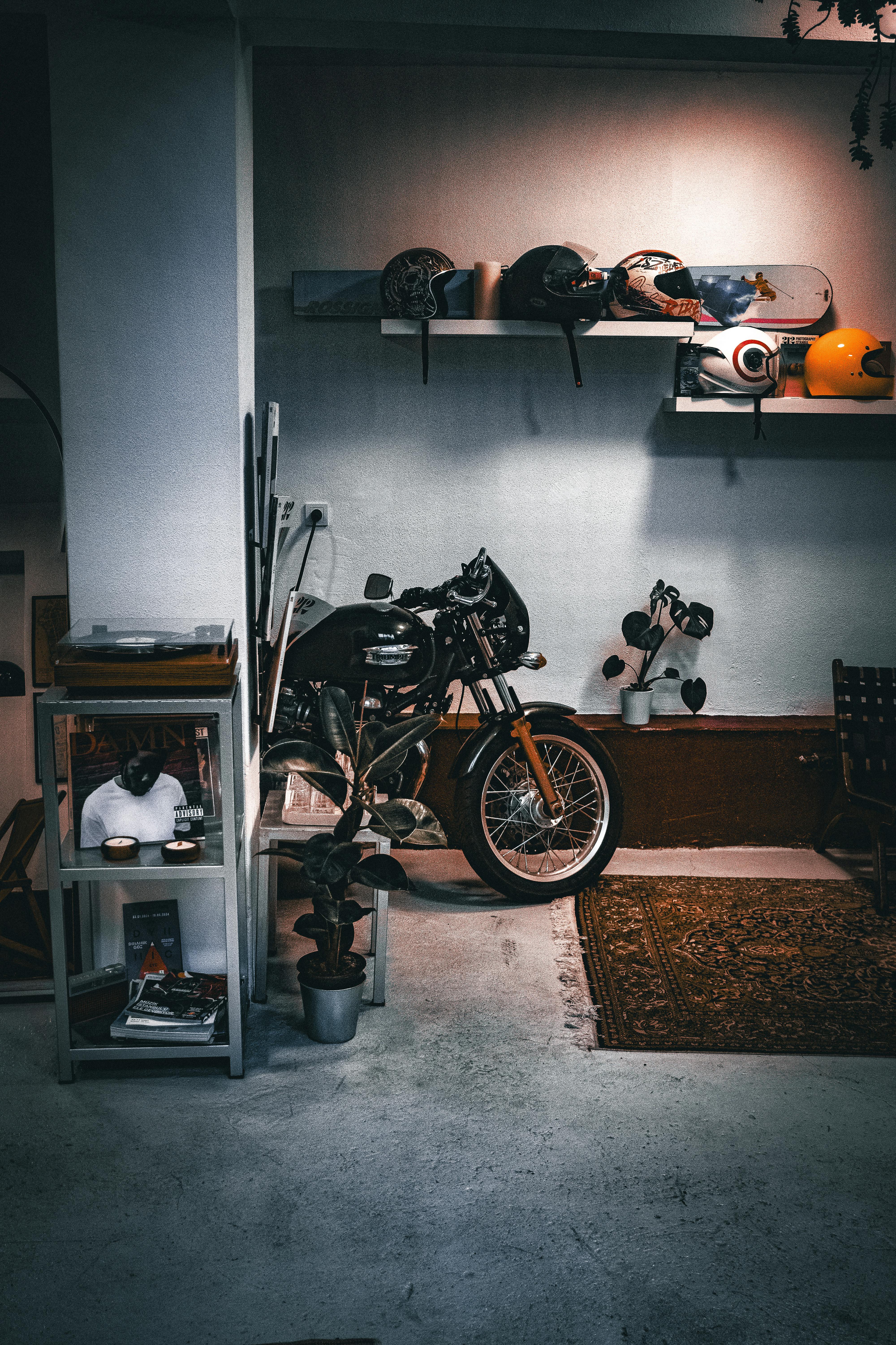 A cozy indoor setup featuring a motorcycle, helmets, and decor. Ideal for motorbike enthusiasts.