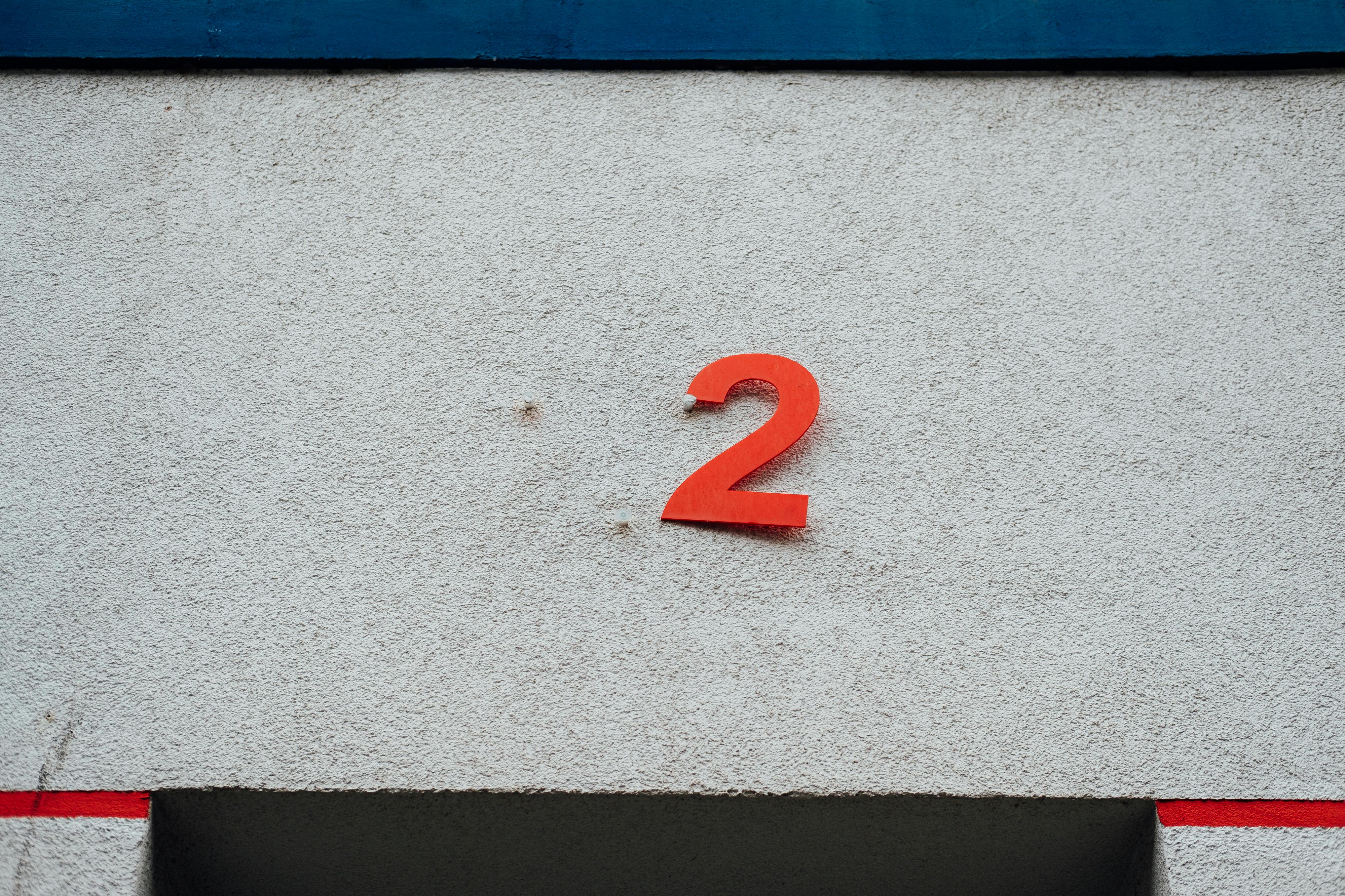 ฟรี ตัวเลข 2 สีแดงเรียบง่ายบนผนังคอนกรีตพื้นผิวมีองค์ประกอบการออกแบบที่เรียบง่าย คลังภาพถ่าย