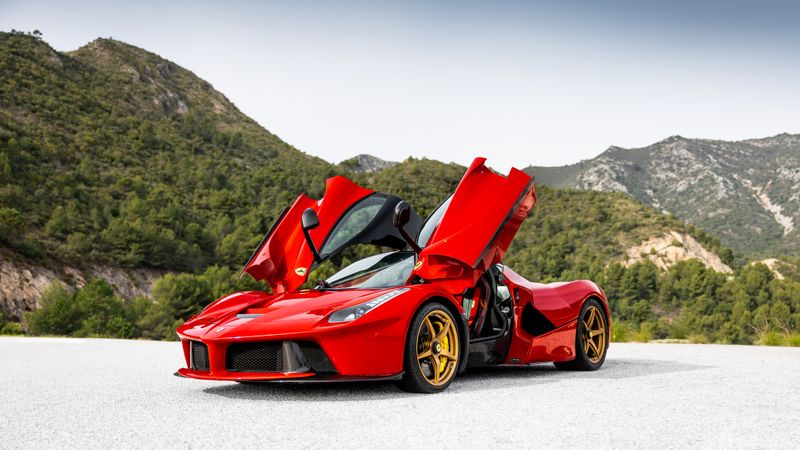 Red convertible with doors open in the mountains