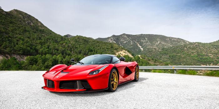 A striking red sports car parked on a scenic mountain road.
