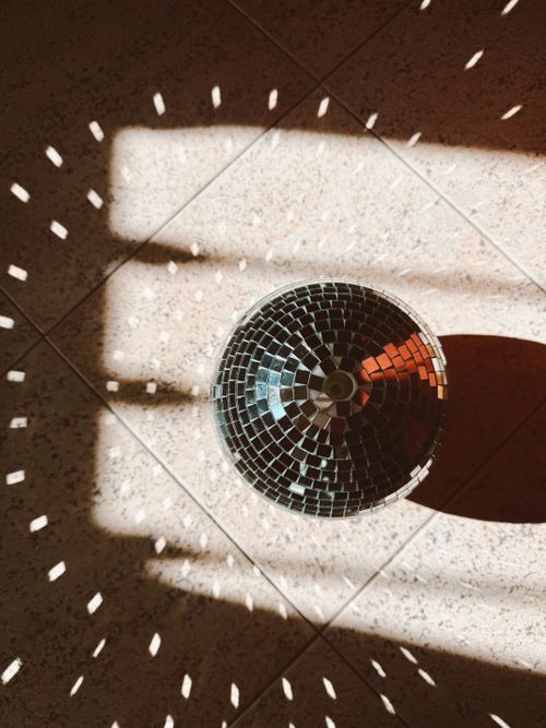 Free A top-down view of a disco ball casting dazzling light reflections on tiled floor. Stock Photo