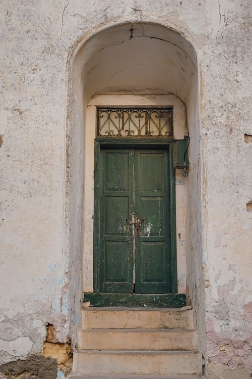 Free A vintage green wooden door set in an aged stone archway, showcasing rustic charm. Stock Photo