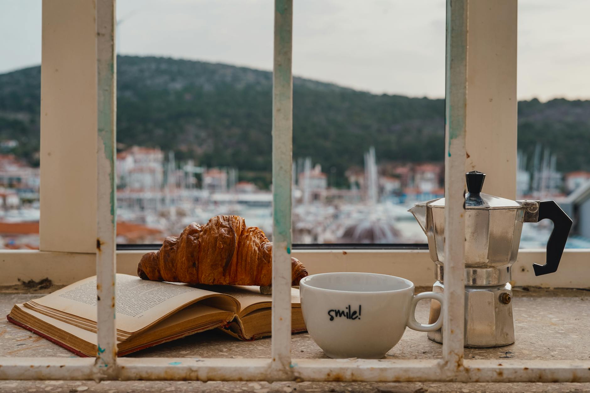 Travel Like A Pro: Tips For Booking The Perfect Flight And Hotel Combo 1 relaxing morning setup with a croissant, moka pot, and coffee cup on a windowsill overlooking a marina.