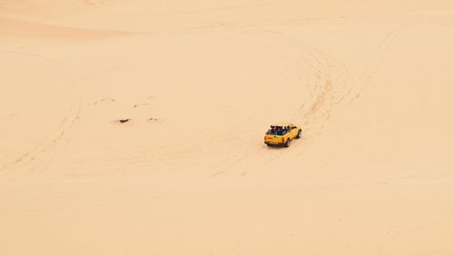 Free A yellow jeep navigates vast desert dunes, showcasing adventure and exploration. Stock Photo