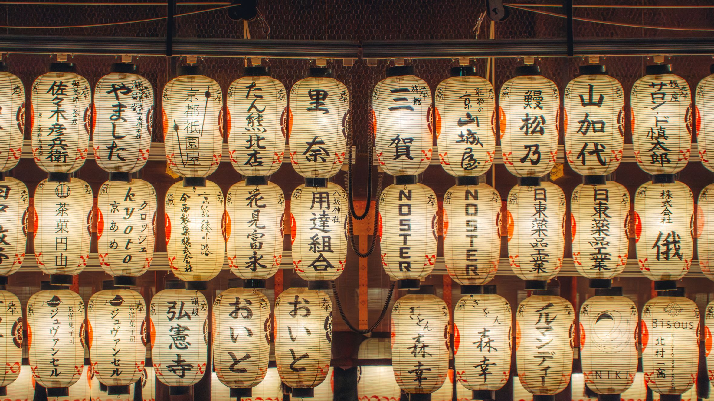 A beautiful array of illuminated Japanese lanterns showcasing decorative kanji in a nighttime setting.