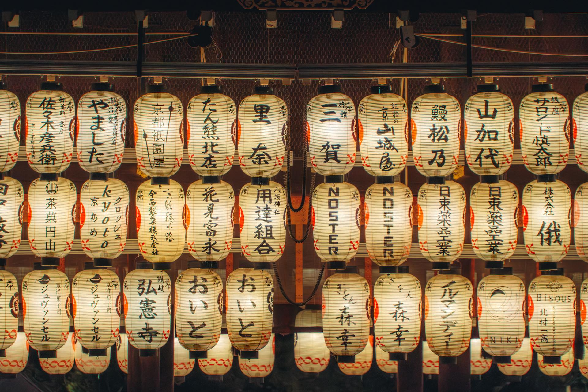 A beautiful array of illuminated Japanese lanterns showcasing decorative kanji in a nighttime setting.
