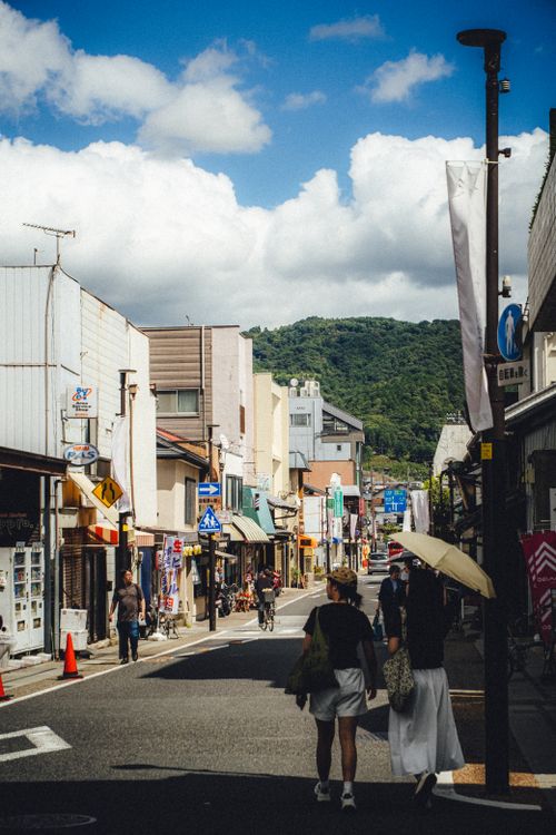 Free Street scene in a Japanese town with people walking and mountains in the background. Stock Photo