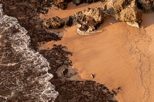 Breathtaking aerial shot of a tranquil beach in Bali with rocky shorelines and gentle waves.