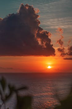A vibrant sunset over the ocean in Bali, Indonesia, with dramatic clouds and a colorful sky.