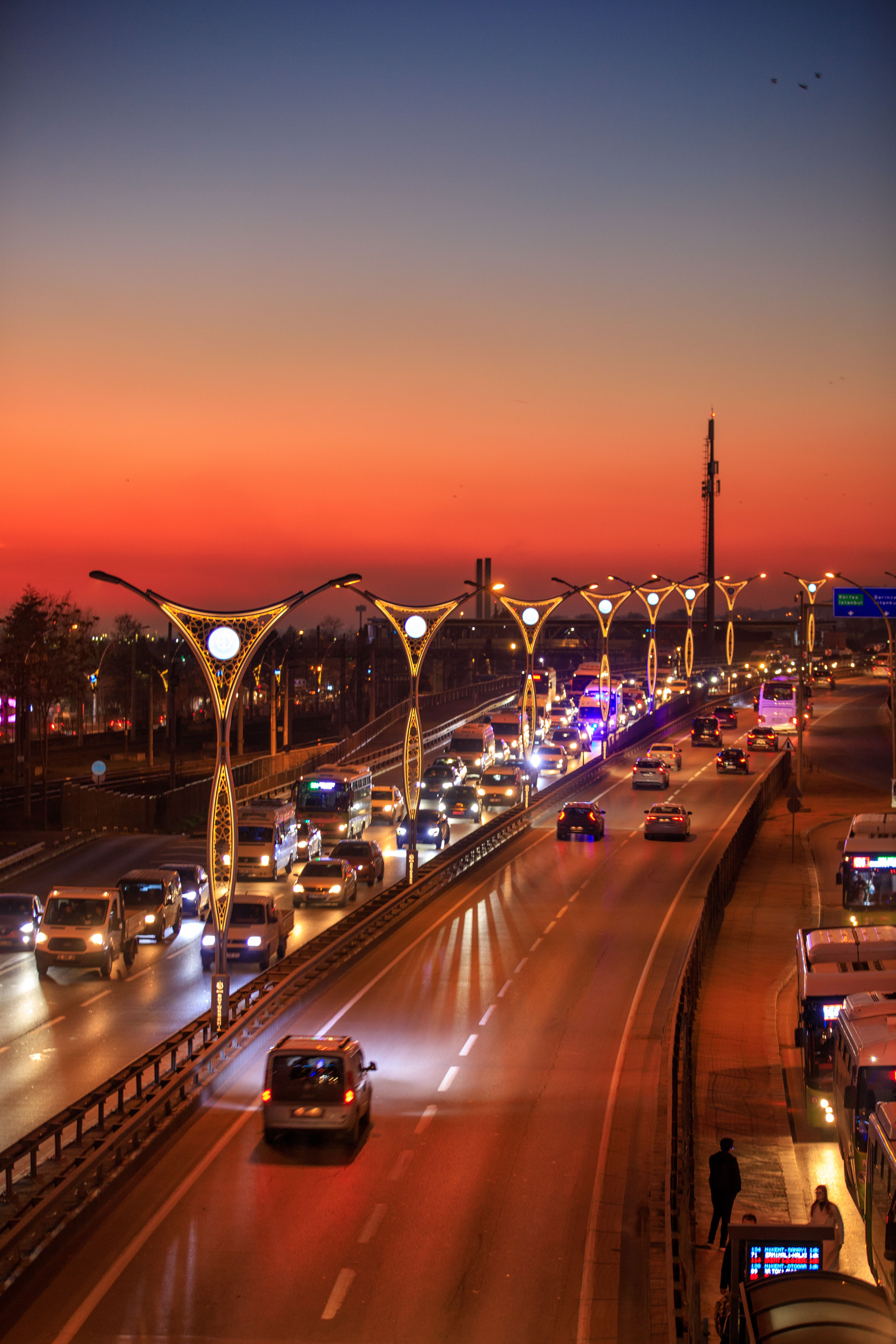 Bustling traffic on D100 highway at sunset in İzmit, Türkiye, with vibrant sky.