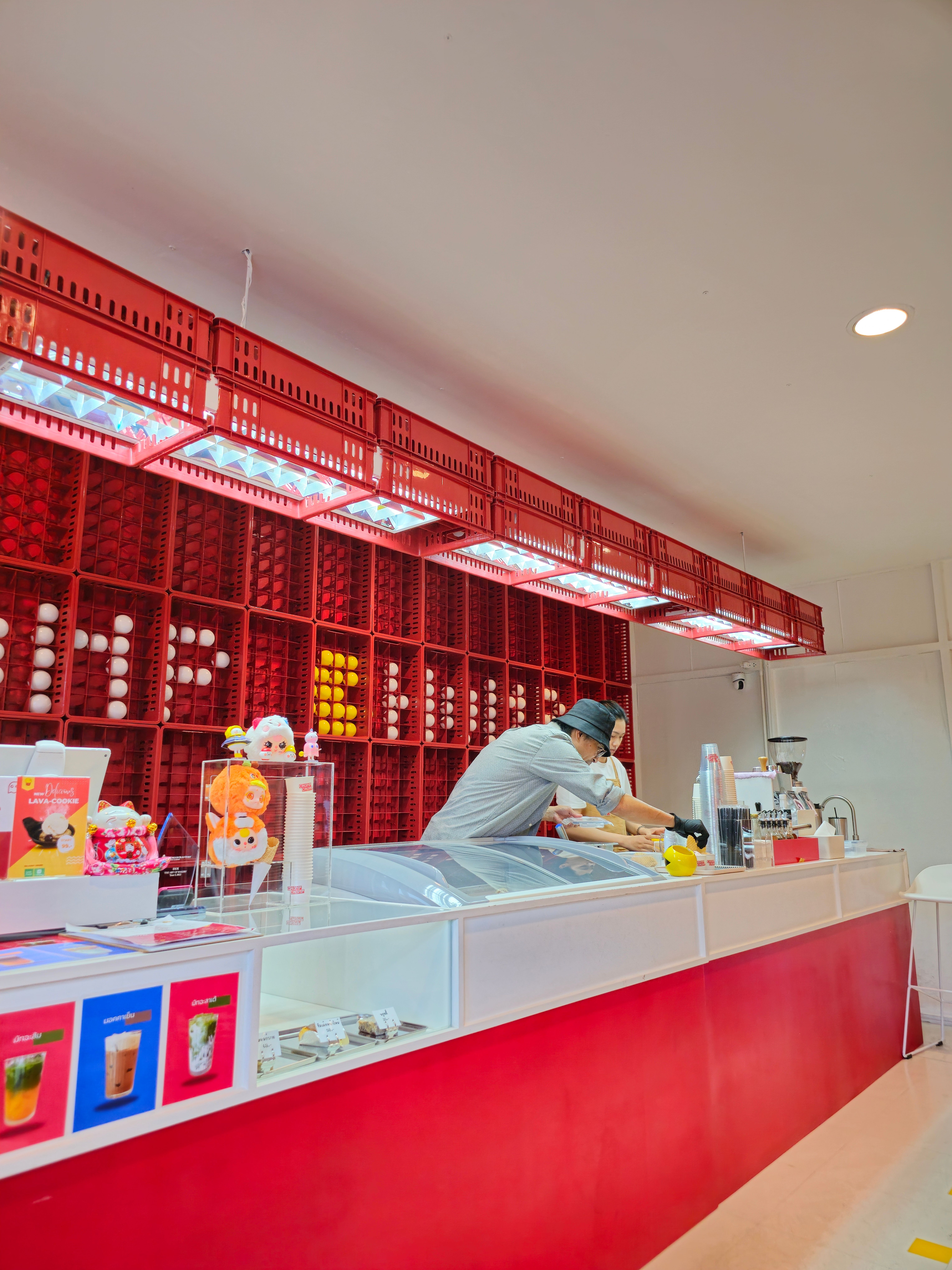 Interior of a vibrant ice cream shop with red decor and staff preparing desserts.