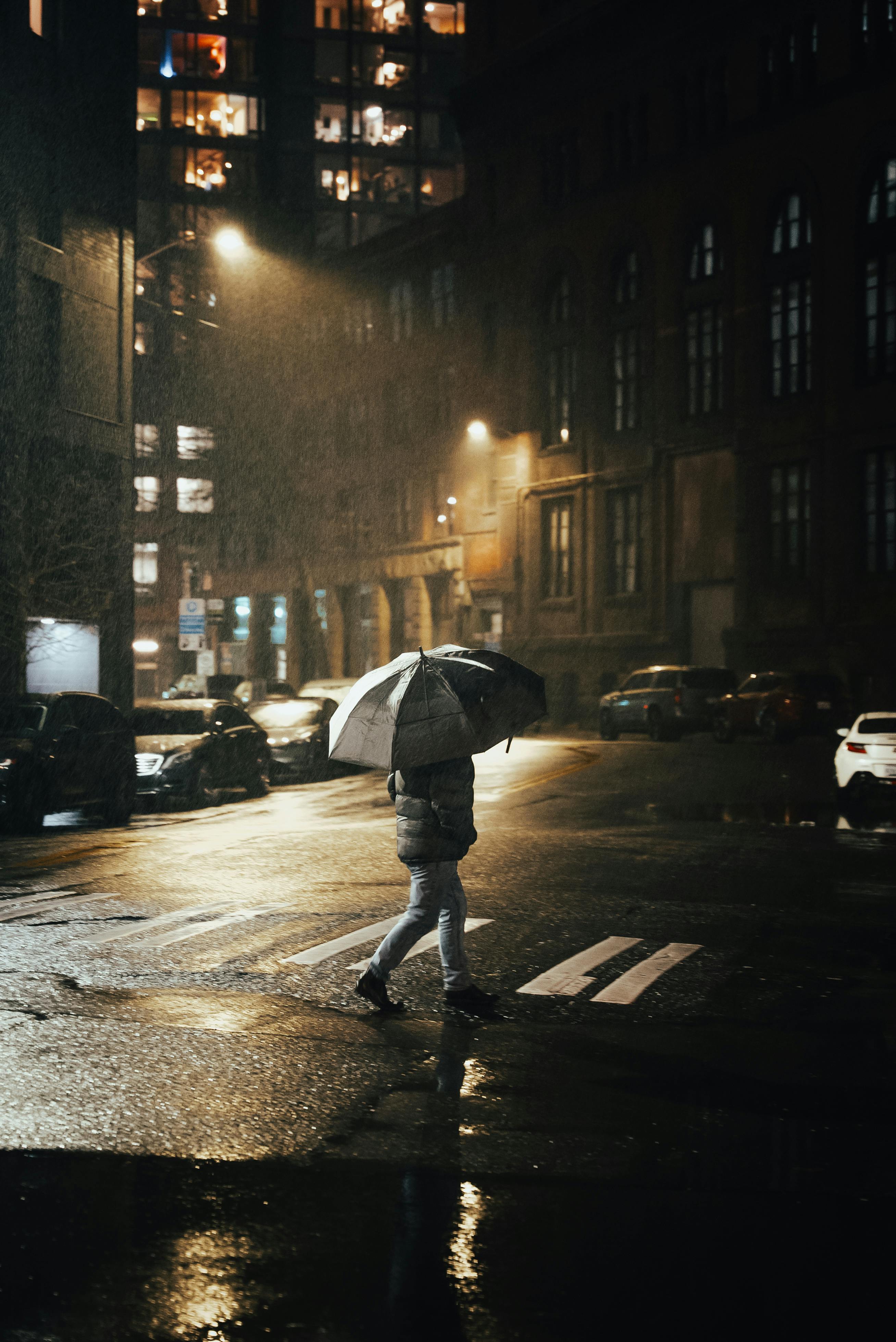 A lone figure walks through a rainy Seattle street at night, illuminated by streetlights.