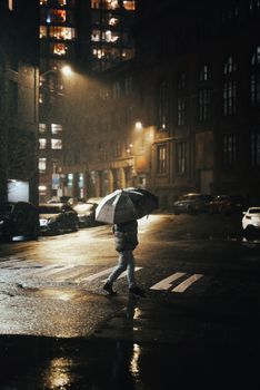 A lone figure walks through a rainy Seattle street at night, illuminated by streetlights.