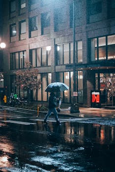 Atmospheric street photo depicting a rainy Seattle night with a lone person under an umbrella.
