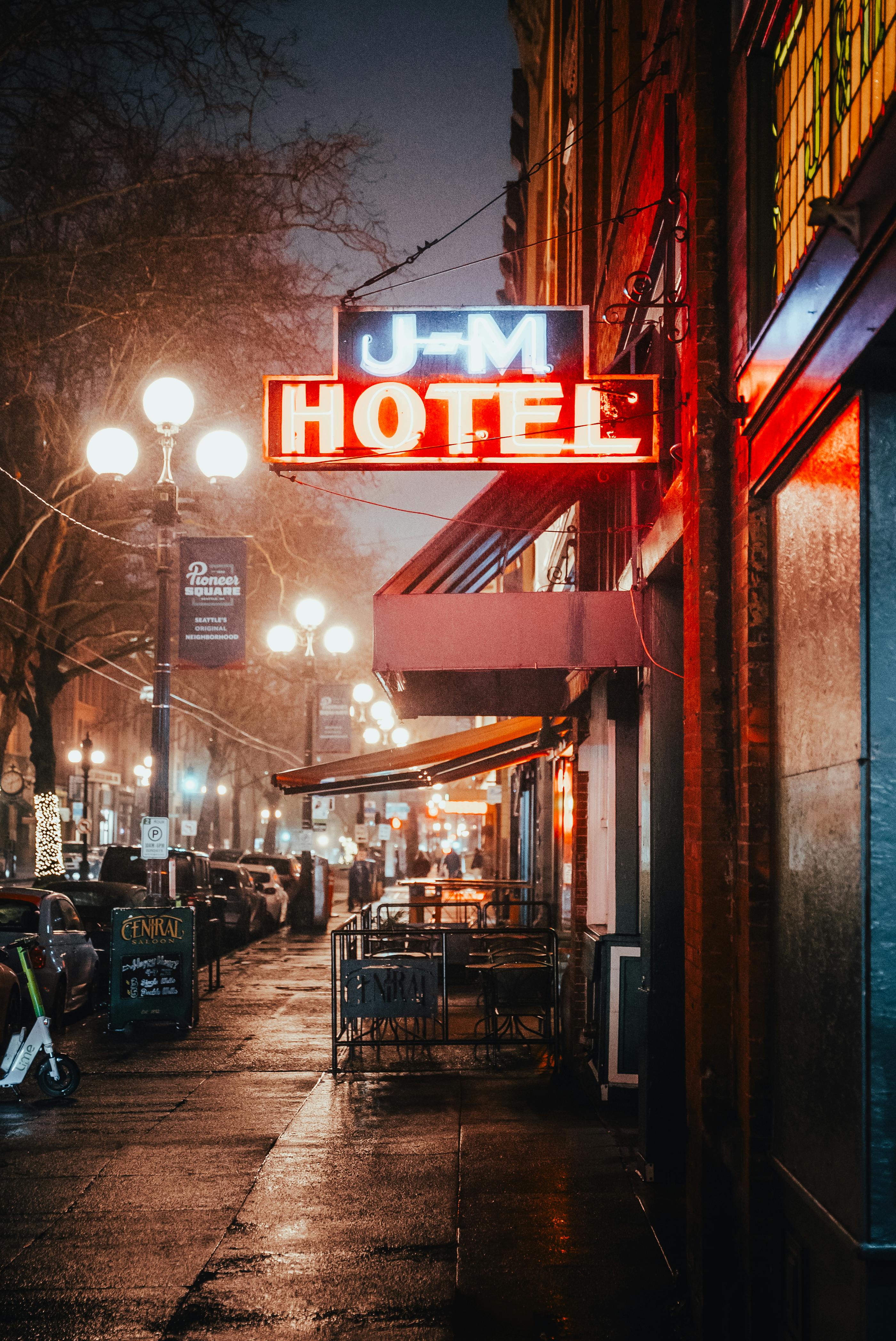 A moody urban street view in Seattle with neon hotel sign and wet pavement at twilight.