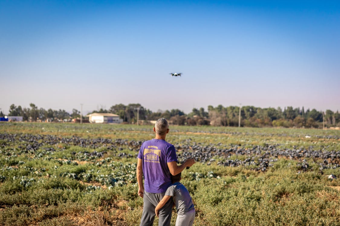 Человек в фиолетовой рубашке, стоя на траве поля