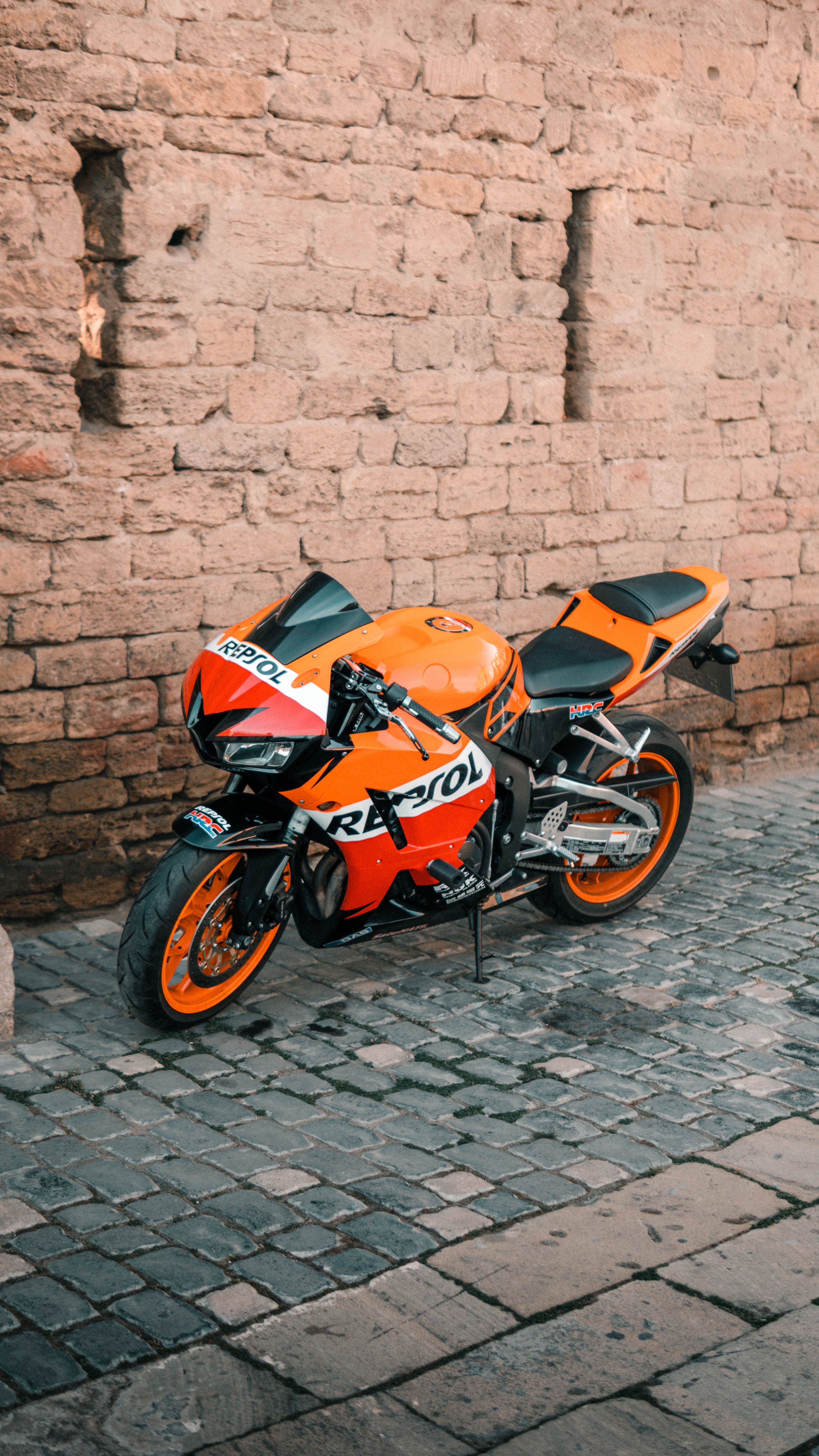 Vibrant Orange Sports Motorcycle by Stone Wall · Free Stock Photo