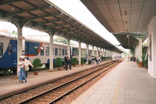 Passengers at a bustling train station platform on a cloudy day.