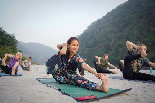 Group practicing yoga on a serene beach in Bali, Indonesia, surrounded by lush hills.