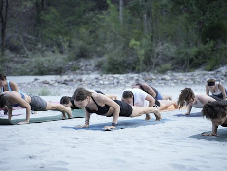 A group practicing yoga on a beach in Bali, Indonesia, surrounded by lush greenery.