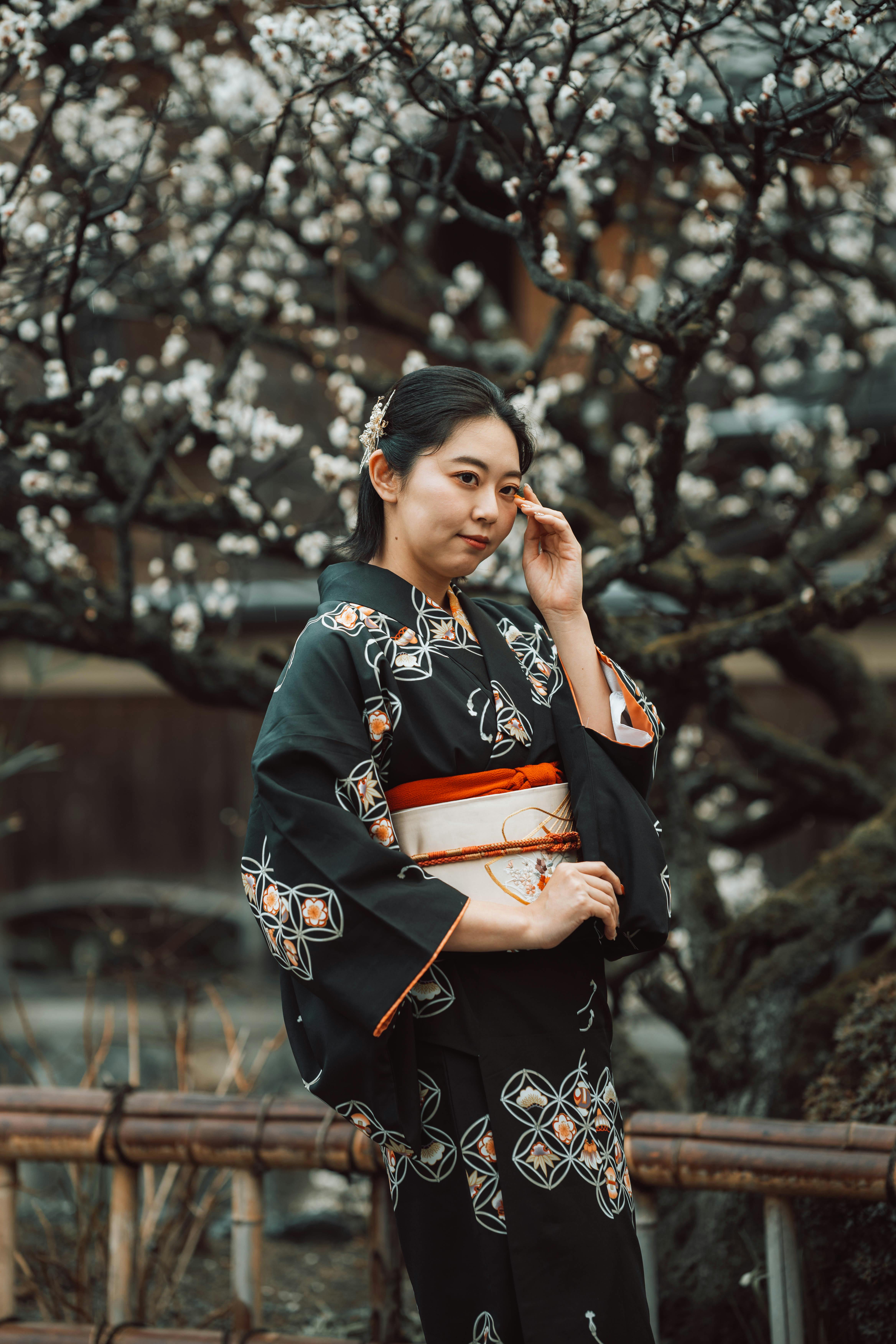 Elegant Japanese woman in kimono amidst cherry blossoms in Kyoto garden.