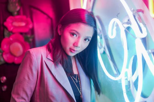 Photo of Woman Posing Next to Neon Sign