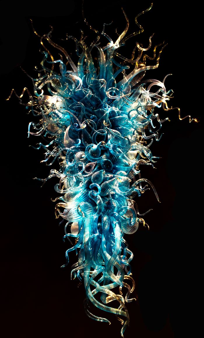 Blown-glass sculpture in blue and amber against black. Photo by james Pervis on Pexels.