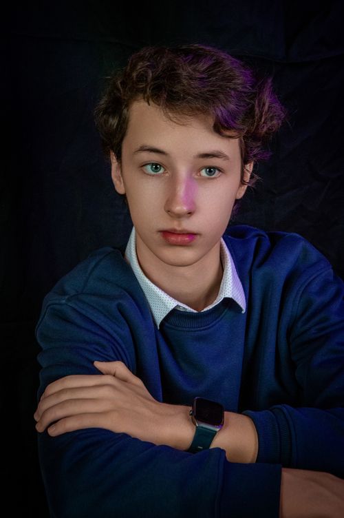 Free Teen boy in blue sweater with smartwatch, neutral expression. Stock Photo